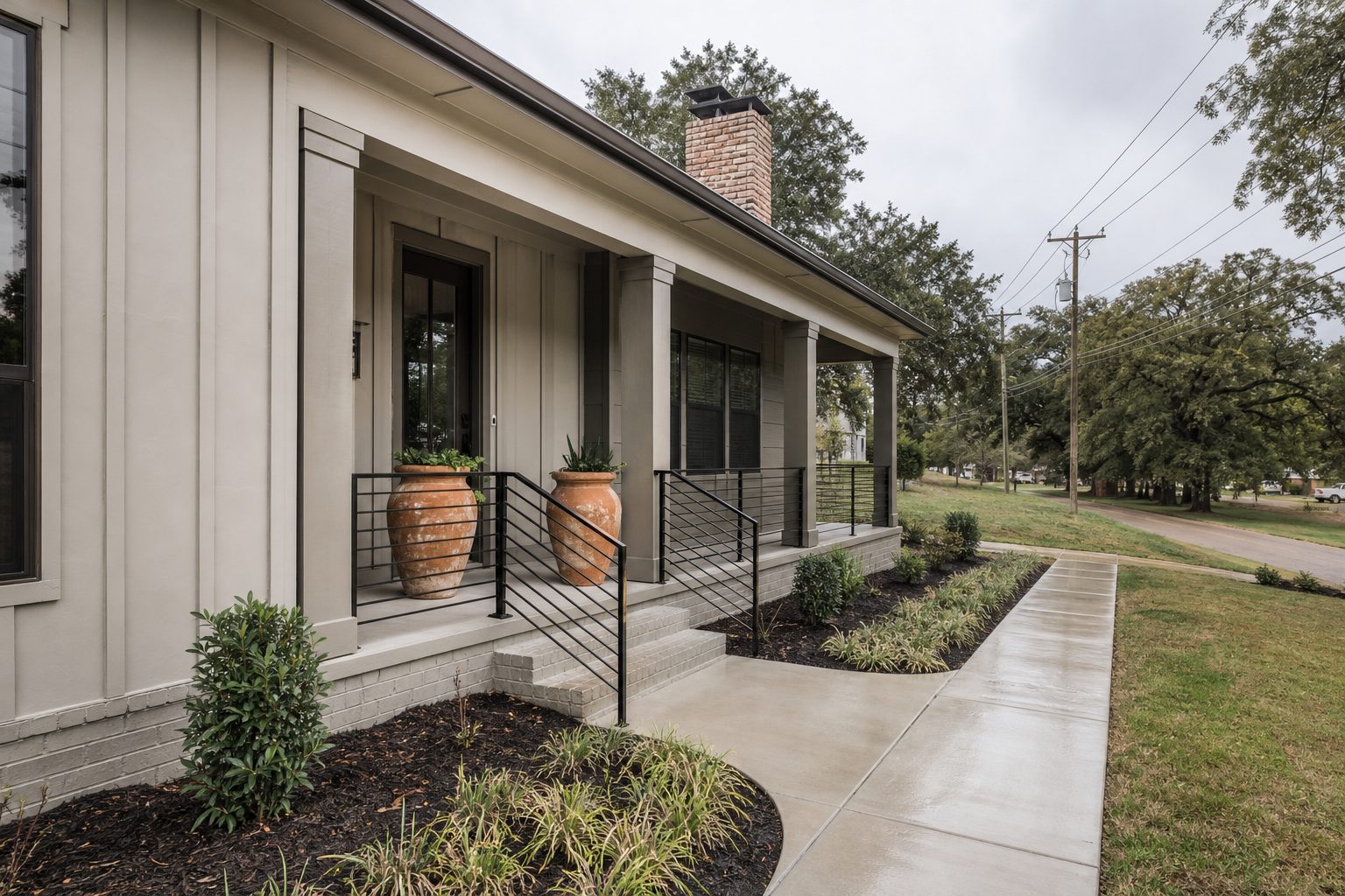 Contemporary Weatherford home with gray siding and brick chimney featuring manicured landscaping and entry portico.