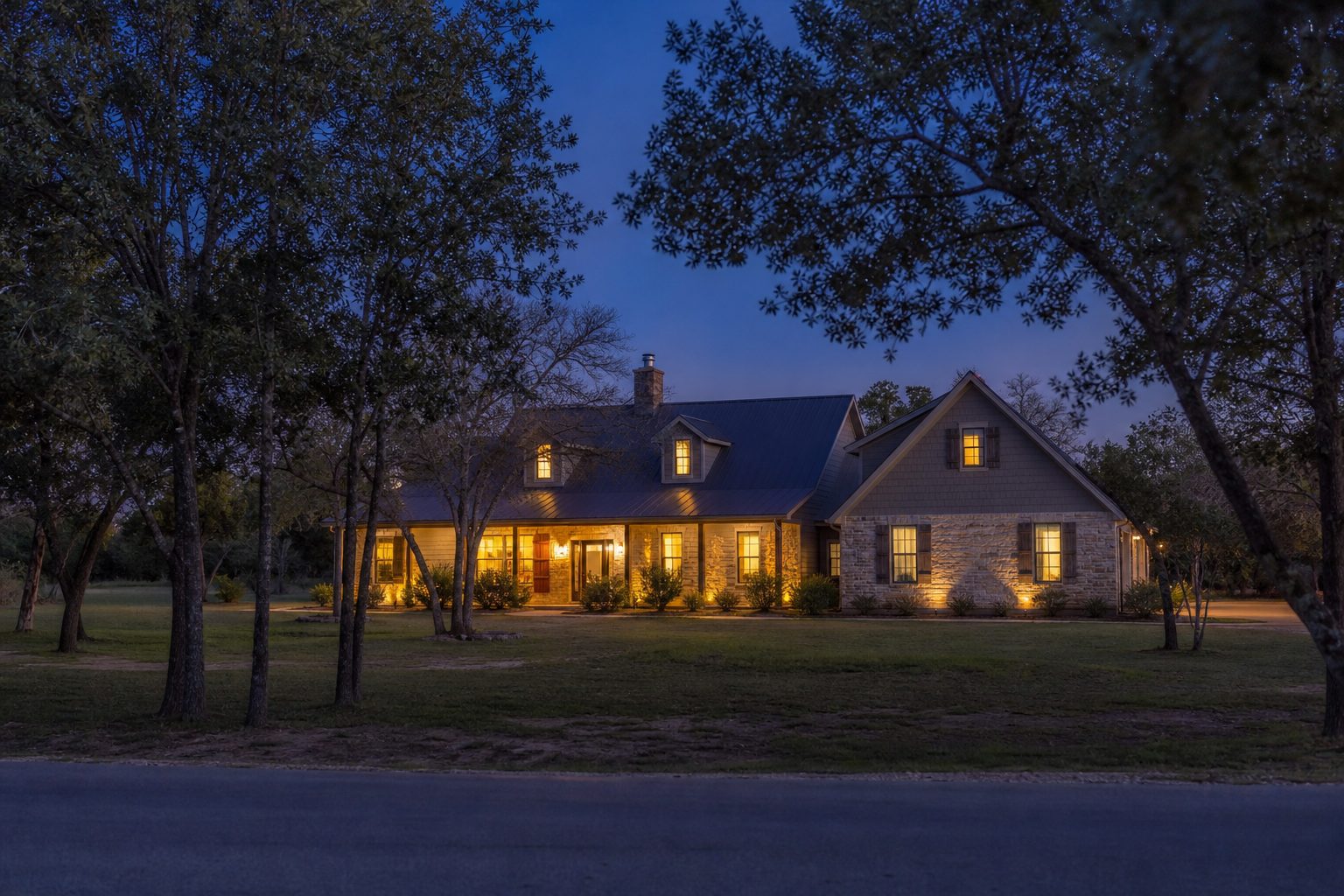 Rural Parker County home with spacious mature lot and warm interior lighting during evening blue hour.