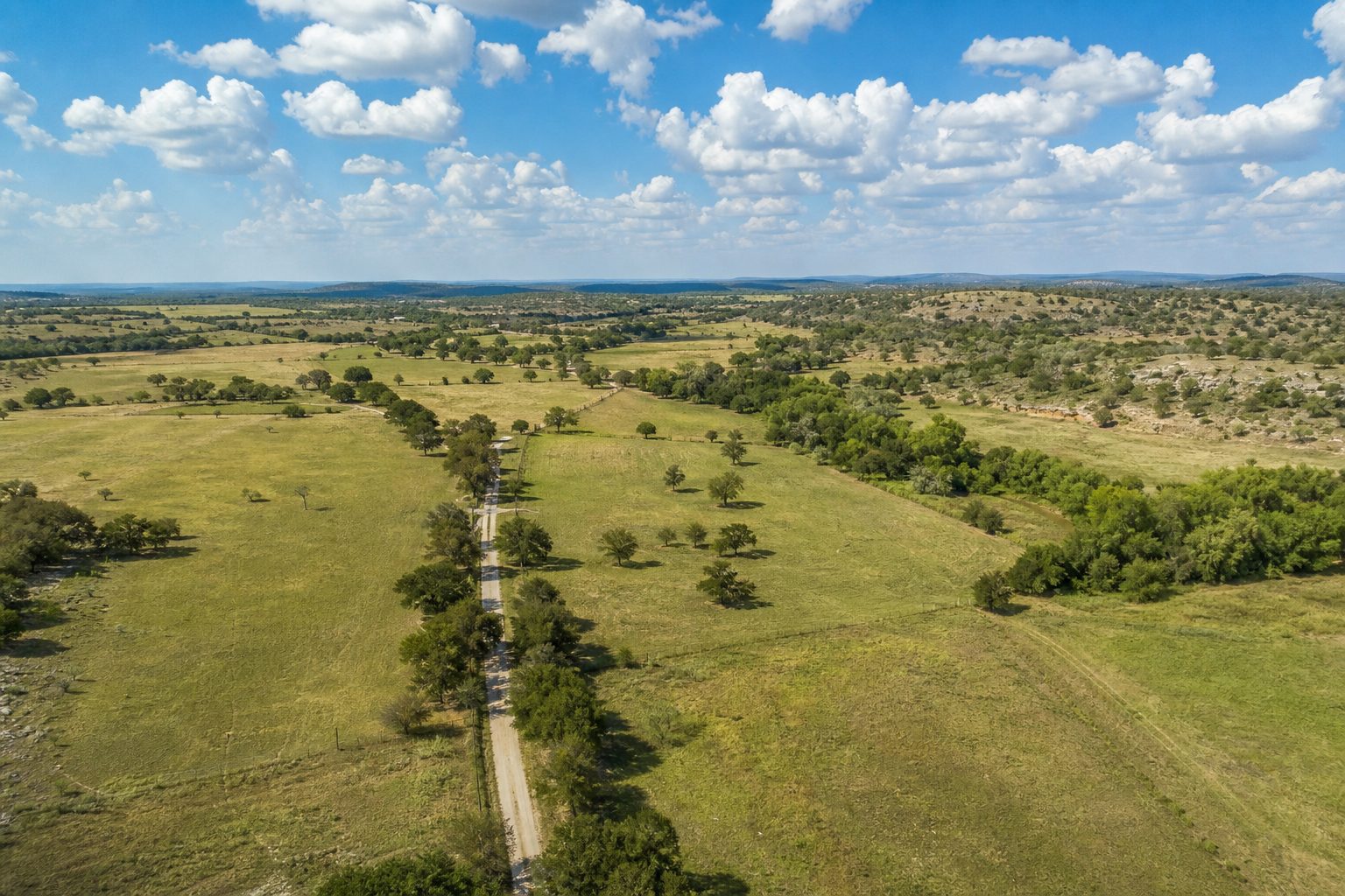Multi-paddock ranch property with deeded road frontage, oak canopy, and creek valley in Palo Pinto County cattle country.